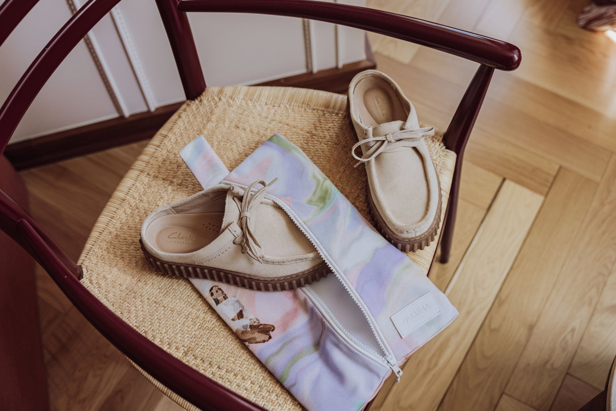 Housse zippée pastel Owaïna avec chaussures beiges sur une chaise en rotin