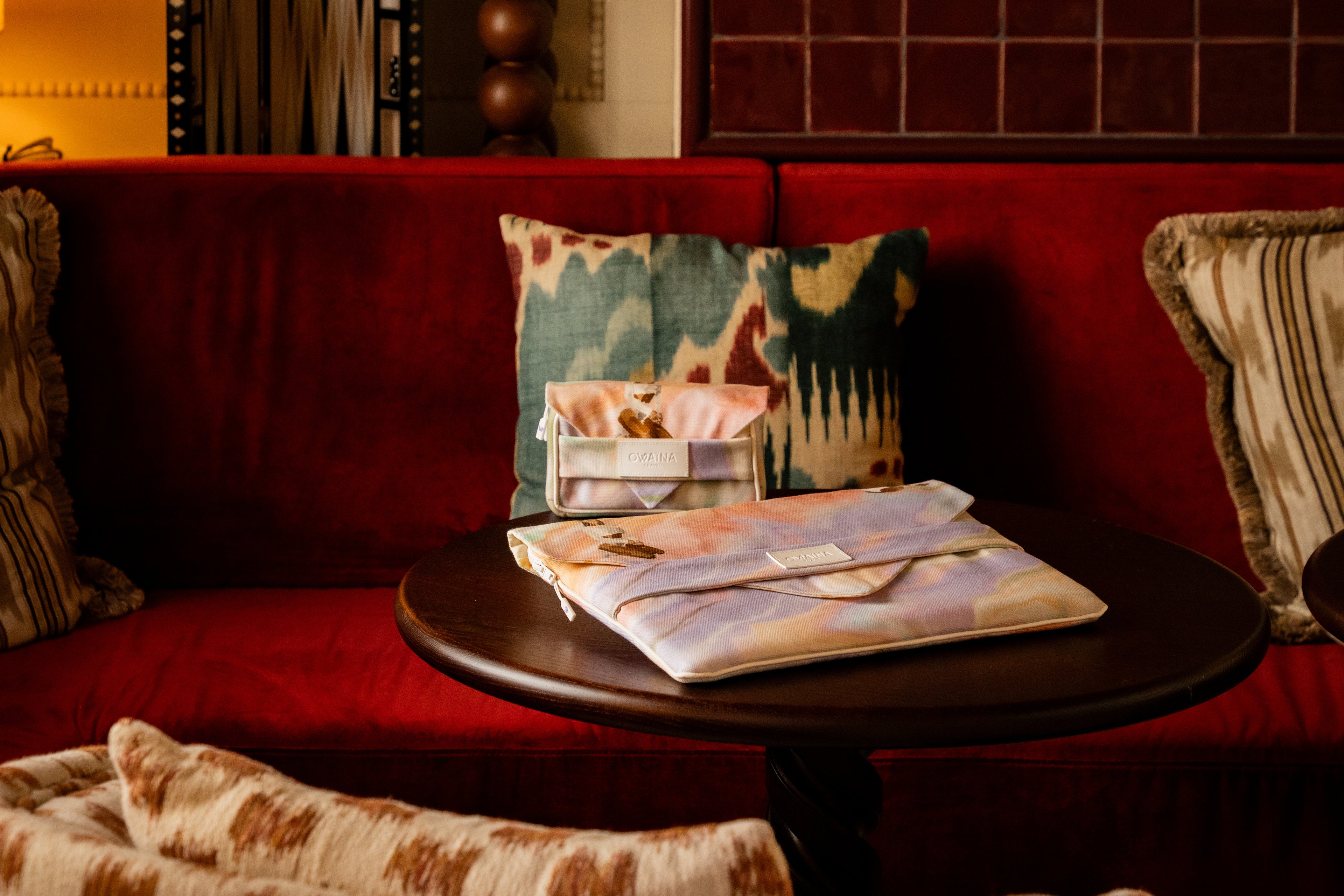 Duo housse ordinateur et trousse à chargeurs sur table salon hôtel.