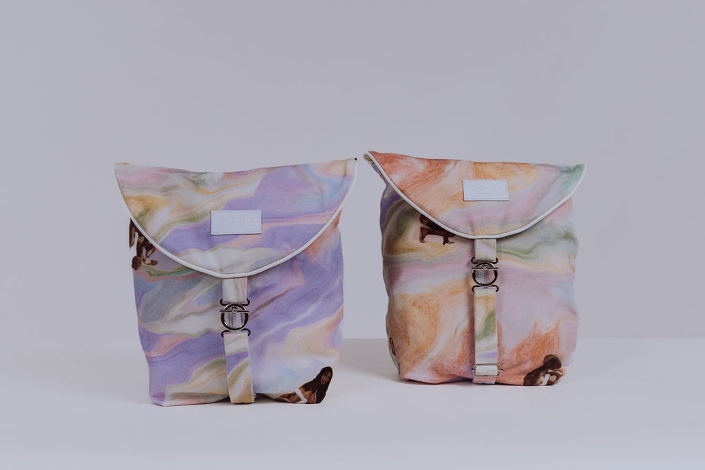 Duo sacs à vêtements de voyage Owaïna pastel avec rabat arrondi et fermoir métallique argenté, présenté en duo sur fond blanc minimaliste.