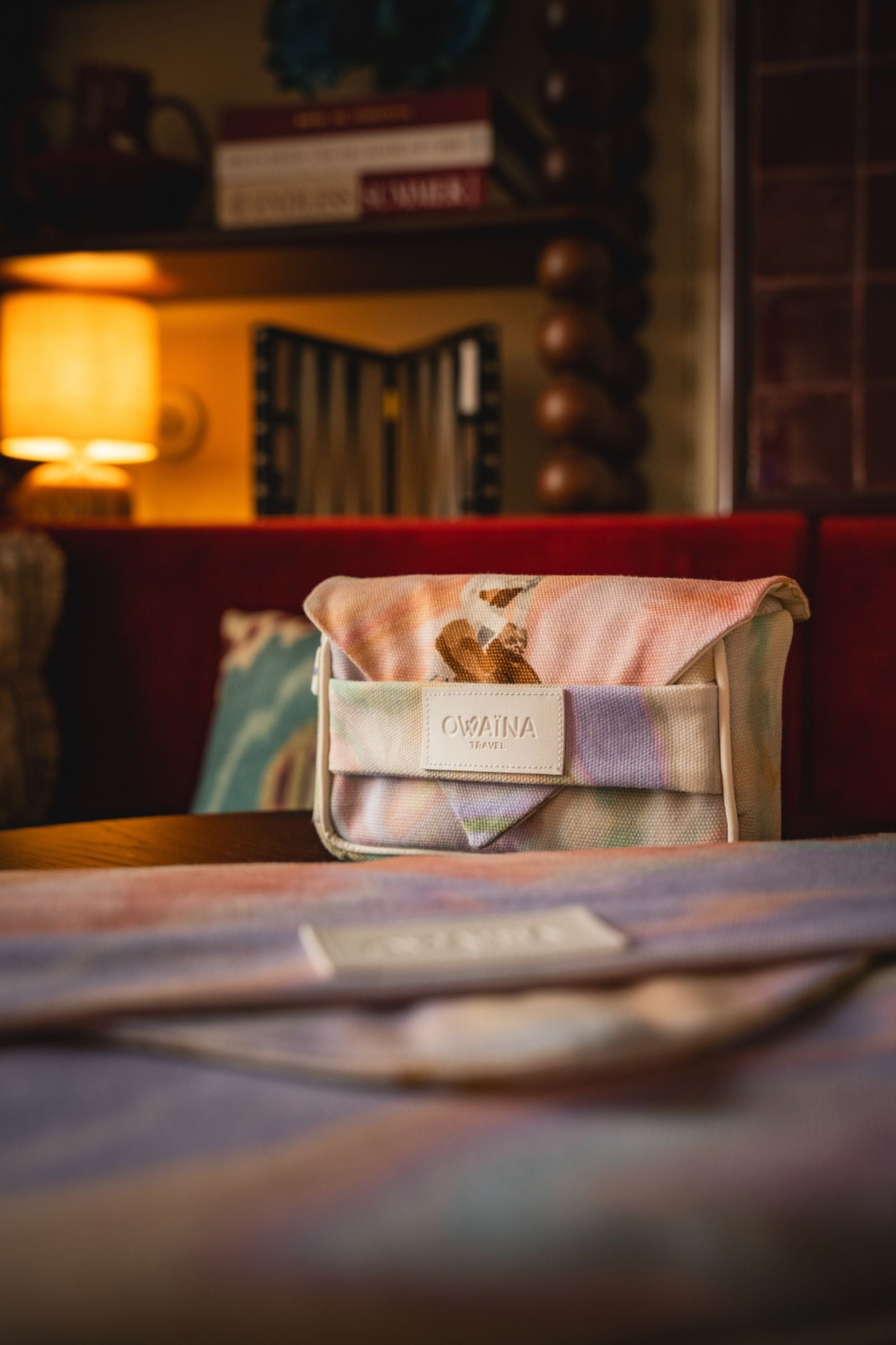 Gros plan sur une trousse à chargeurs avec double compartiments Owaïna pastel marbrée avec logo embossé dans une ambiance lounge élégante.