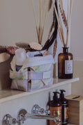 Trousse de toilette à compartiments Owaïna pastel ouverte avec produits de beauté dans une salle de bain élégante et lumineuse.