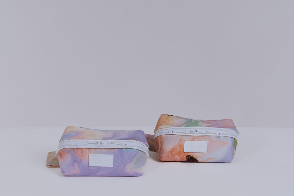 Deux trousses à maquillage Owaïna aux motifs pastel marbrés avec fermeture zippée blanche sur fond blanc.