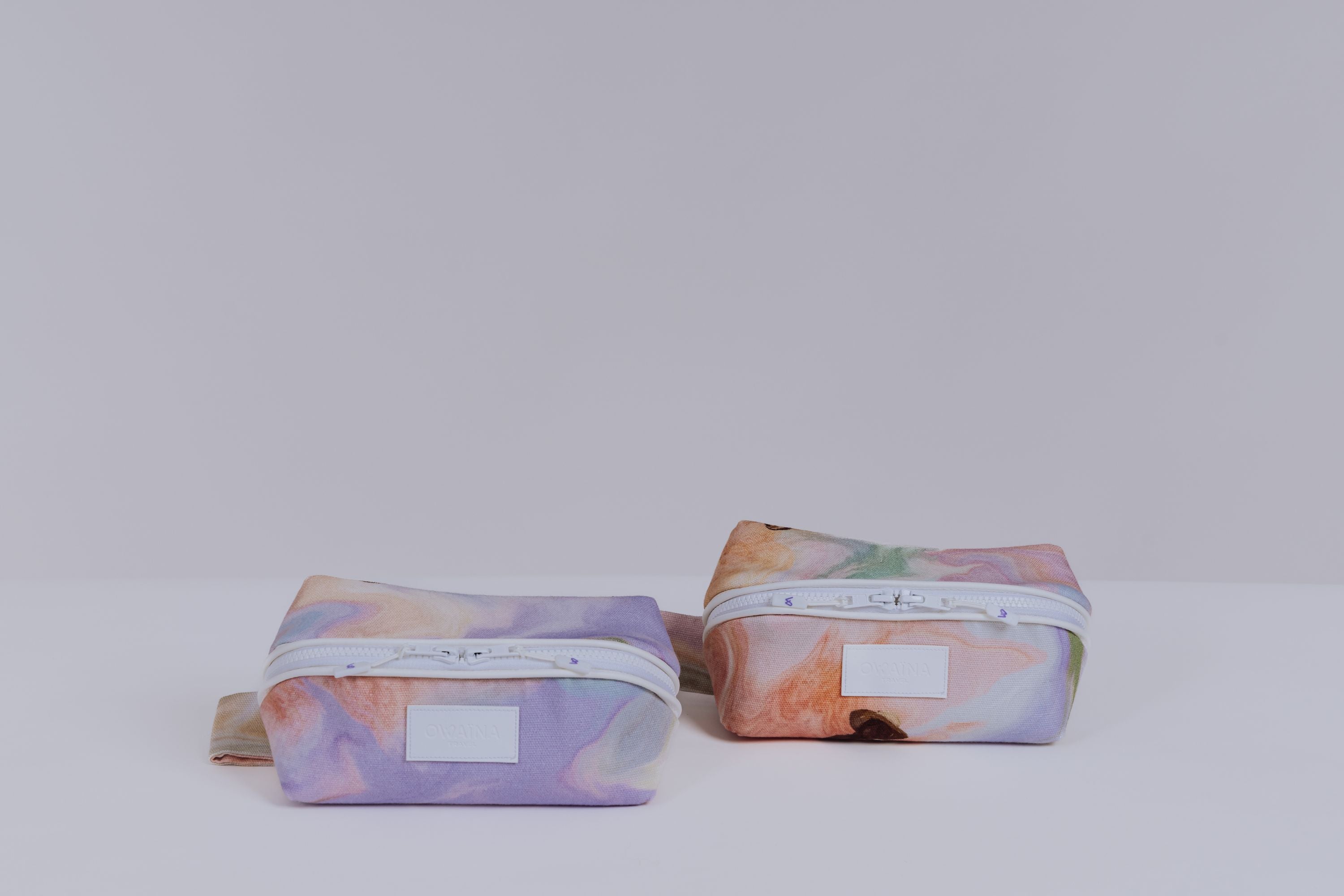 Deux trousses à maquillage Owaïna aux motifs pastel marbrés avec fermeture zippée blanche sur fond blanc.