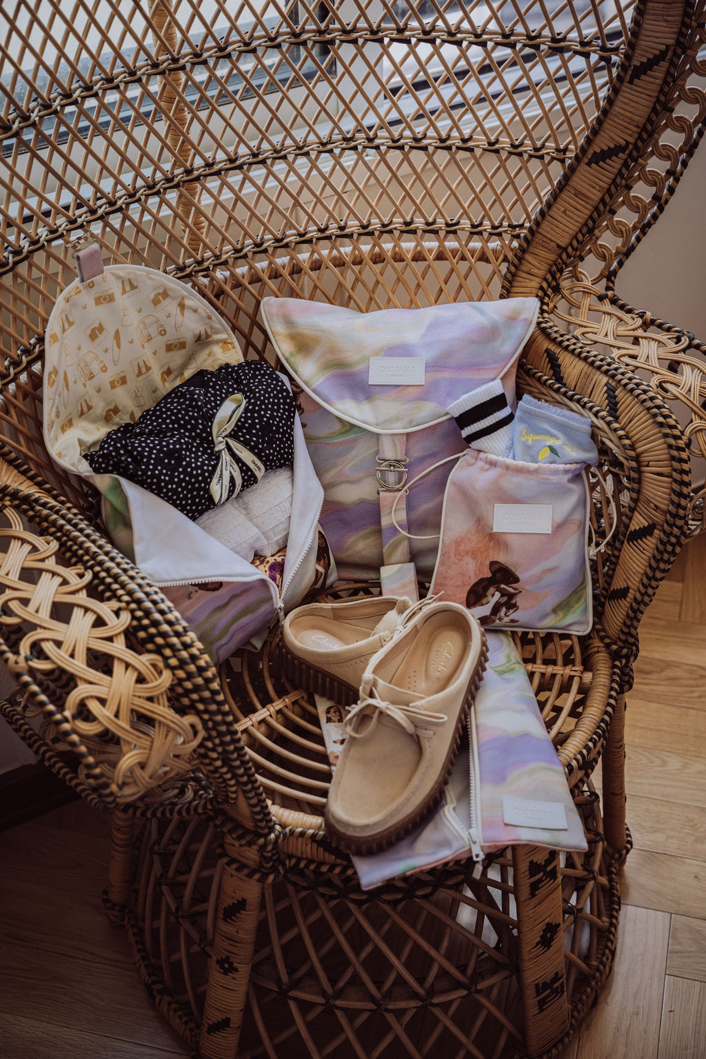Pack de quatre accessoires de voyage pour ranger vêtements, lingerie, chaussures. Placés sur une chaise en rotin dans un hôtel luxueux et lumineux.