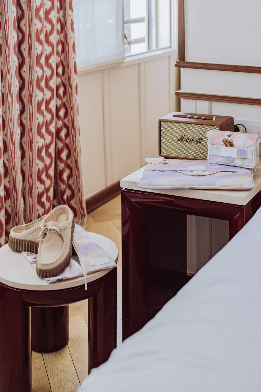 Pack de trois accessoires de voyage pour les voyages business avec une housse à  chaussures, une housse à ordinateur rembourrée et une trousse à chargeur double compartiments. Répartis dans une chambre d'hôtel élégante et luxueuse.
