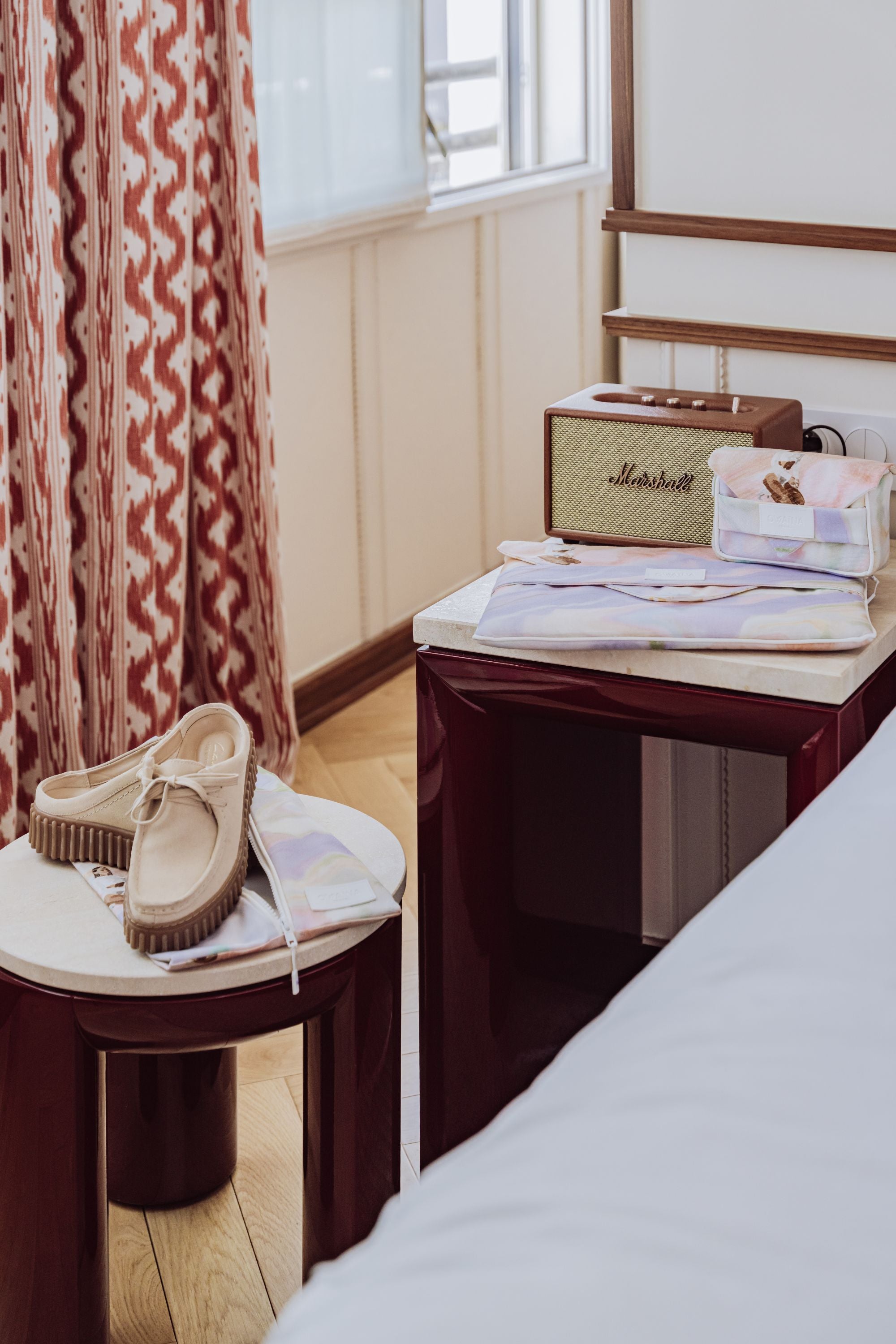 Pack de trois accessoires de voyage pour les voyages business avec une housse à  chaussures, une housse à ordinateur rembourrée et une trousse à chargeur double compartiments. Répartis dans une chambre d'hôtel élégante et luxueuse.