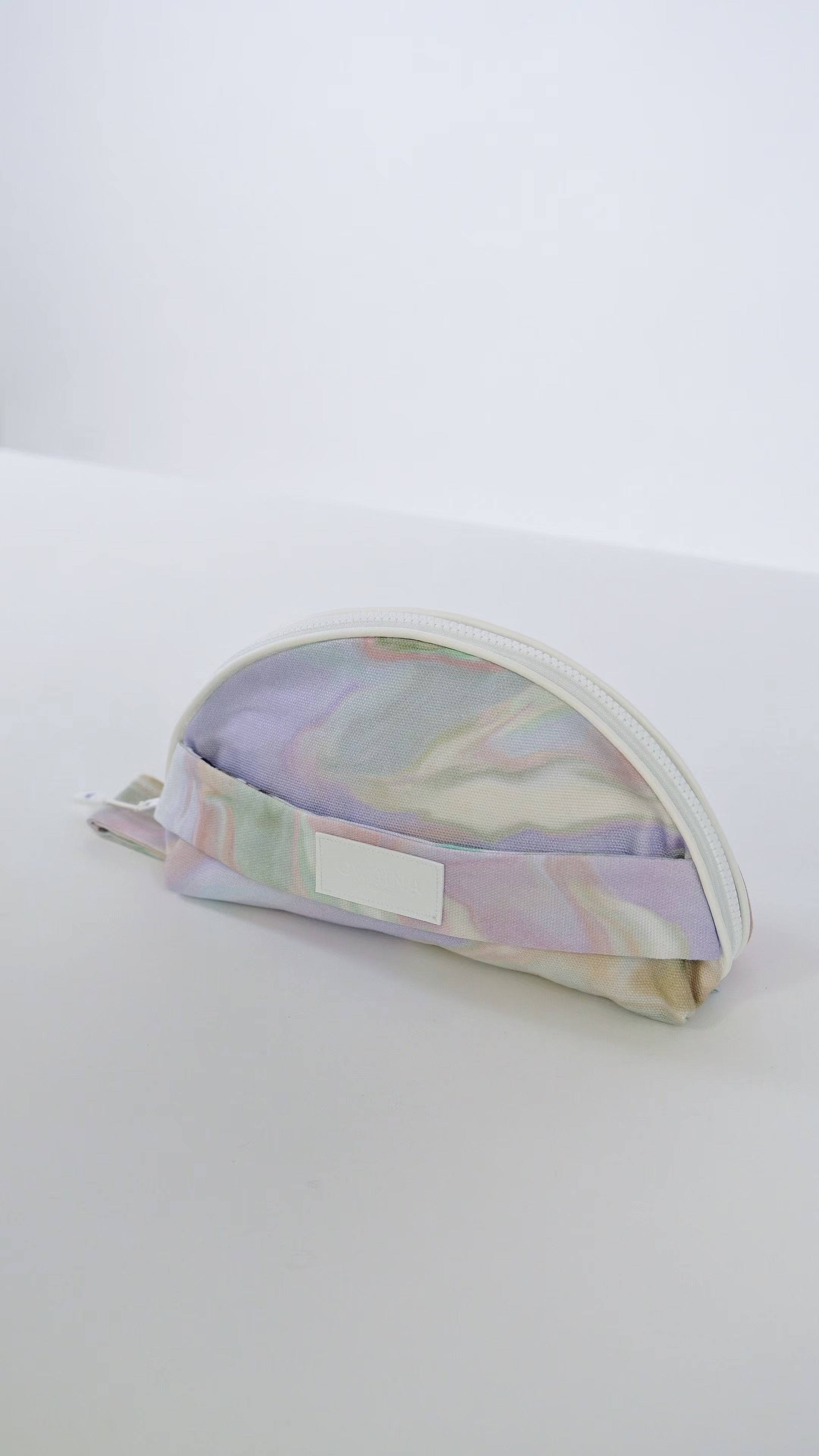 Vidéo trousse à maillot de bain Owaïna pastel marbrées avec fermeture zippée blanche et détails minimalistes.