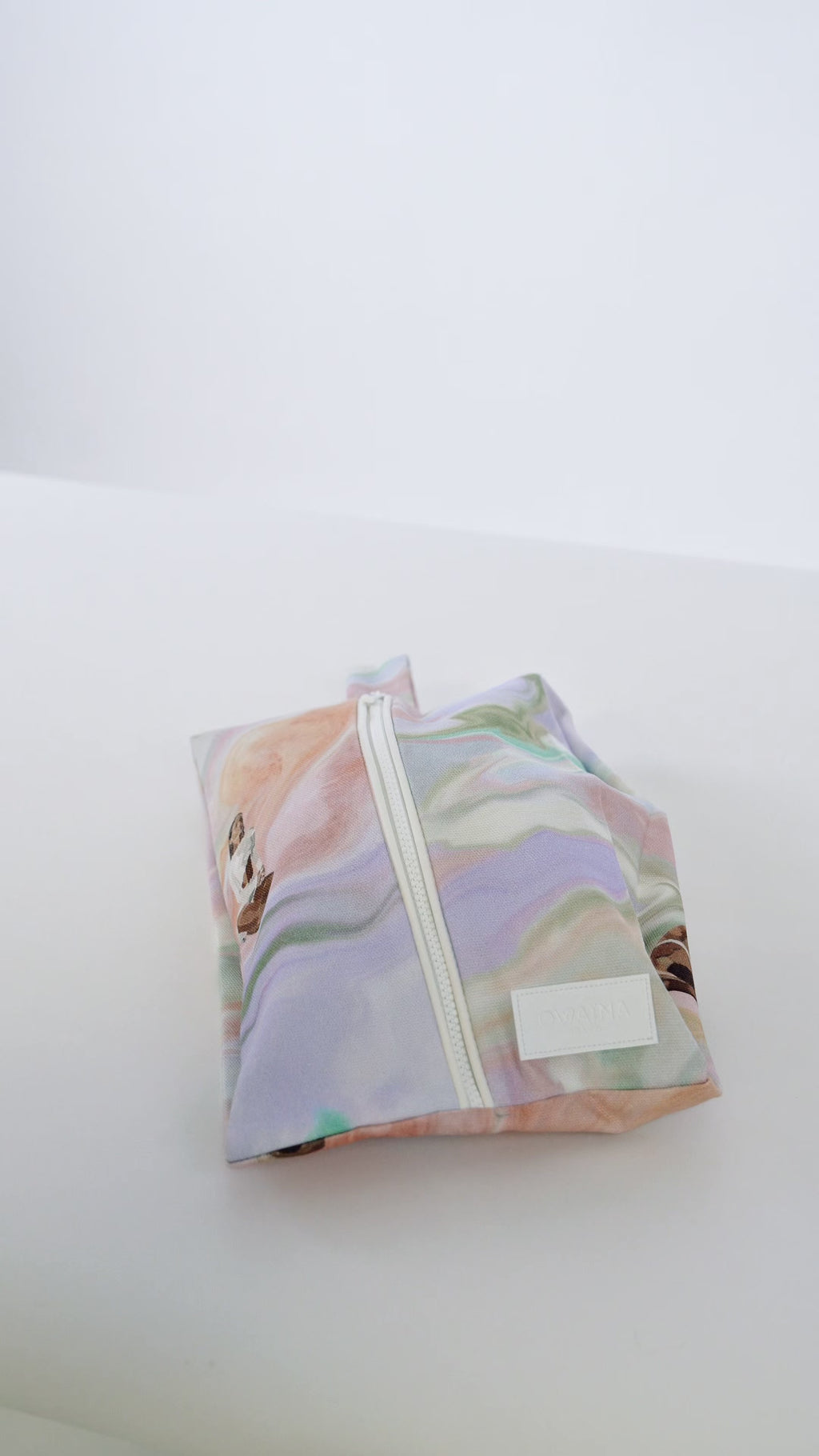 Vidéo chaussures beiges sortant d'une housse à chaussures zippée Owaïna pastel marbrée sur fond blanc.
