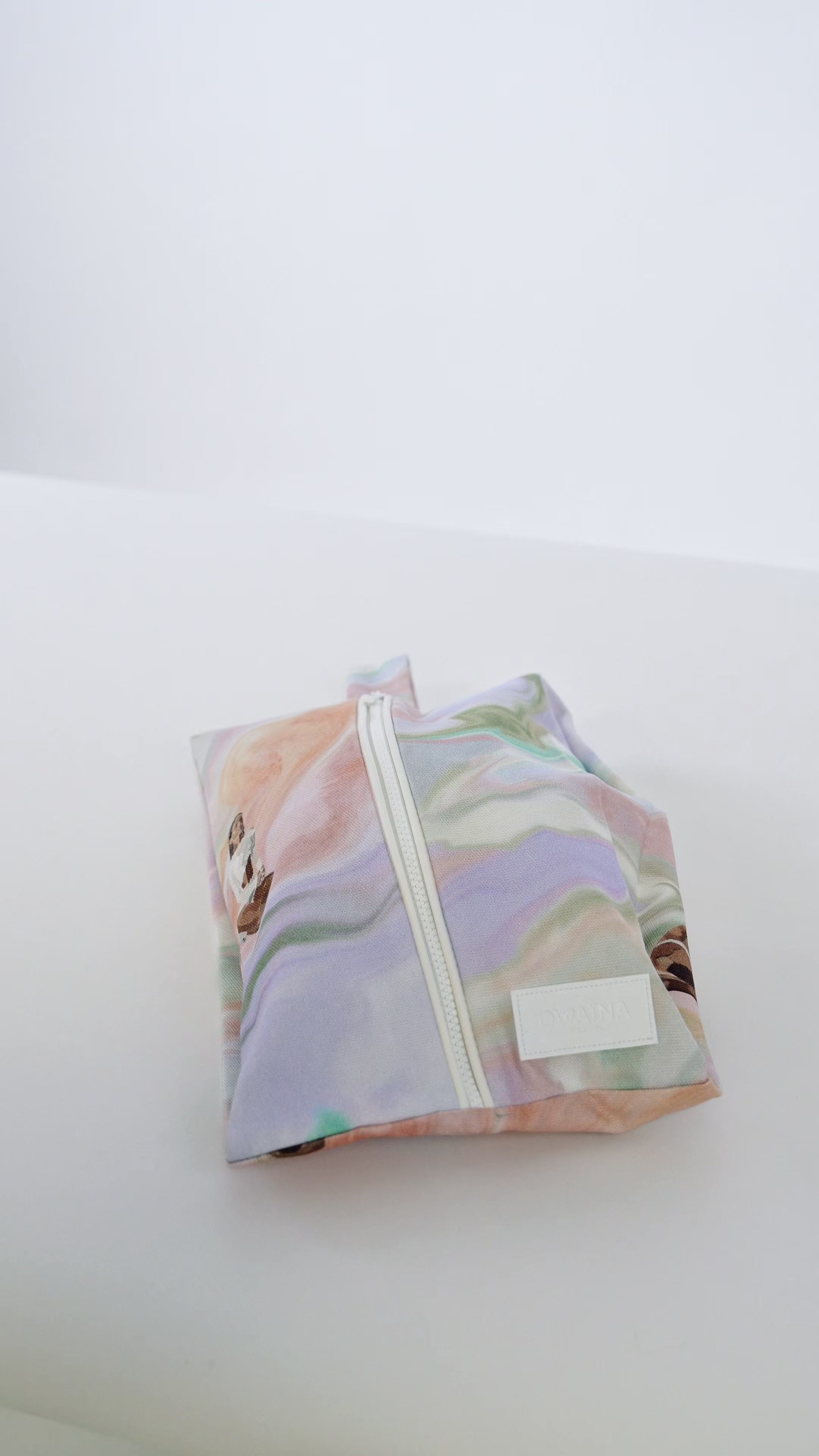 Vidéo chaussures beiges sortant d'une housse à chaussures zippée Owaïna pastel marbrée sur fond blanc.