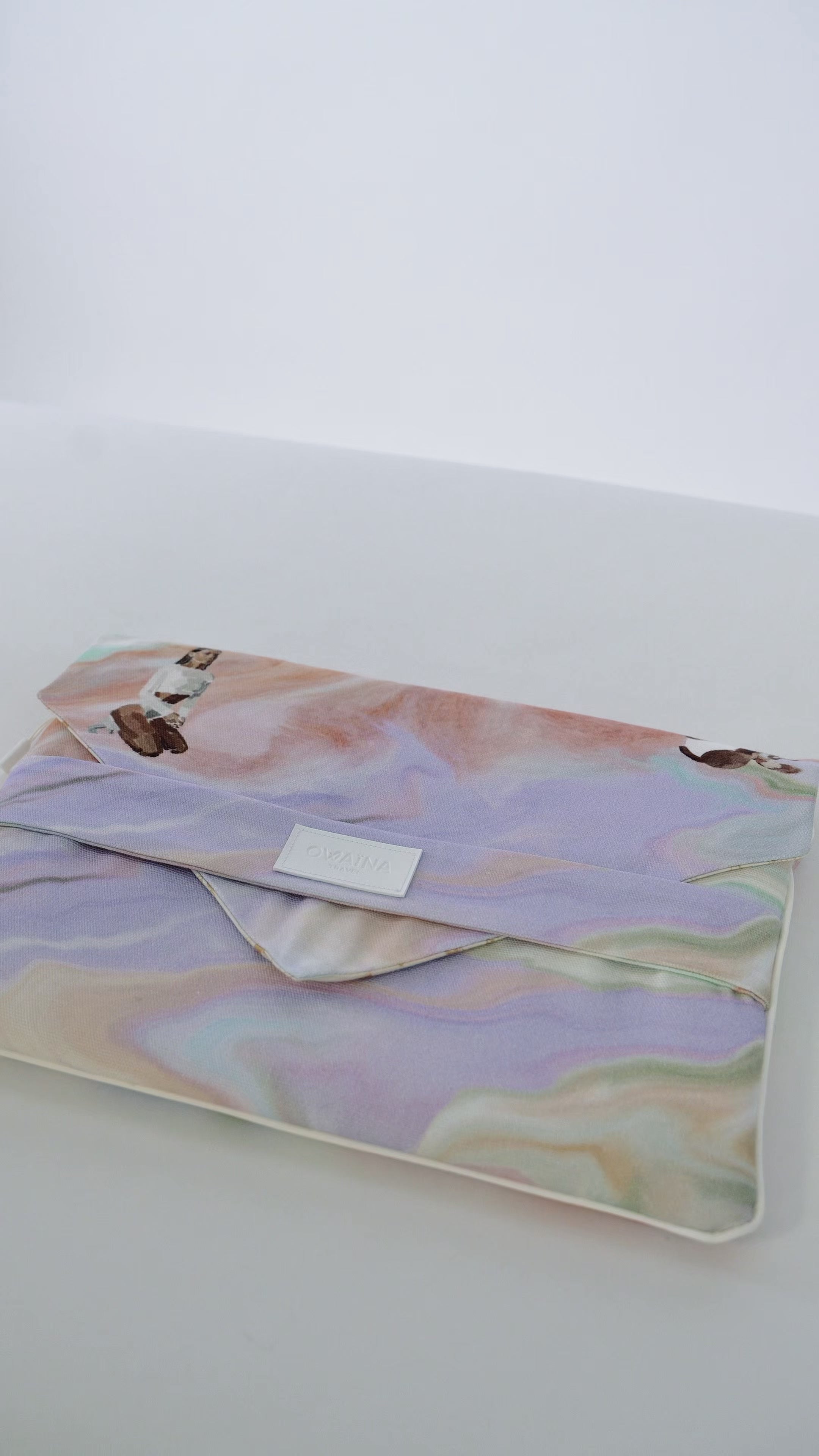 Housse d'ordinateur universelle rembourrée Owaïna pastel marbrées sur fond blanc.