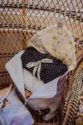 Duo de sacs à vêtements version petit ouvert sur chaise en rotin dans un hôtel boutique.